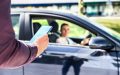 Pasajero solicitando un viaje desde su teléfono mientras un conductor de Uber lo recoge en su automóvil.