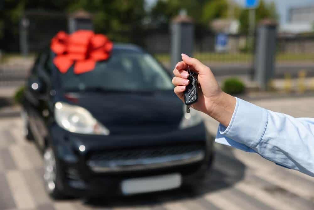 Comprador sosteniendo las llaves de un vehículo recién adquirido mediante un préstamo para autos.