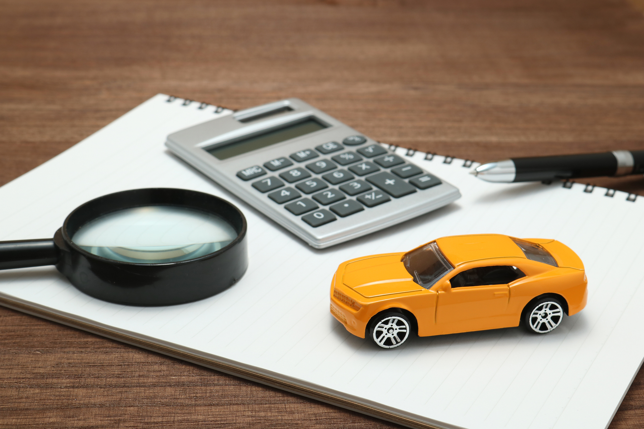 Calculadora, documentos y un modelo de automóvil sobre una mesa, representando los costos y trámites para importar y legalizar un auto en Estados Unidos.