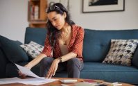 Mujer revisa documentos en casa para cumplir requisitos para asegurar tu casa y organizar su cobertura de vivienda.