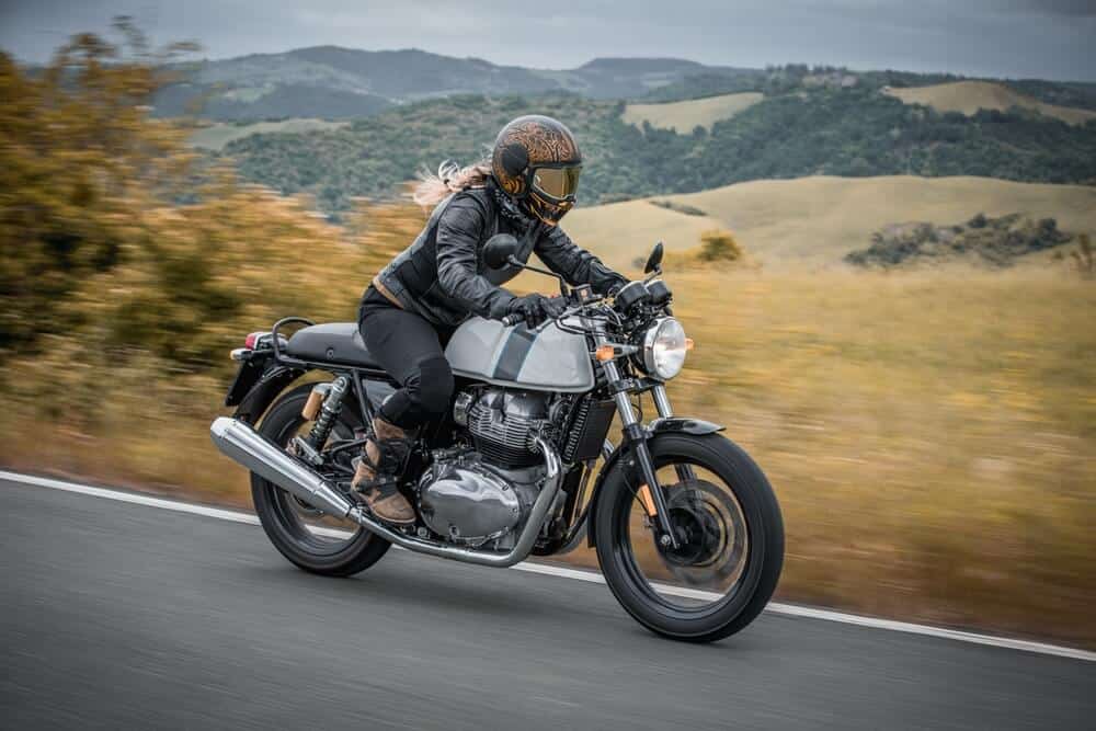 Rider on a vintage-style motorcycle traveling through countryside hills, representing seguro de moto clásica o de colección.