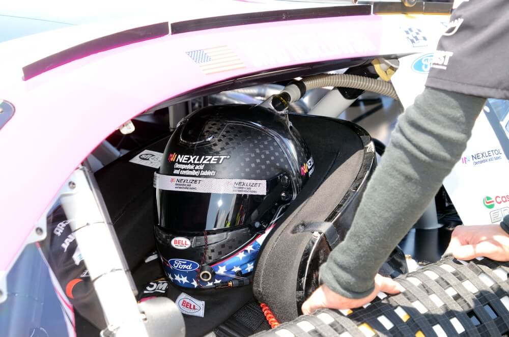Piloto preparándose dentro de un auto de carreras NASCAR, representando los avances tecnológicos y de seguridad en la evolución de los autos de NASCAR.
