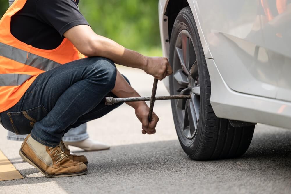 1. Persona cambiando una llanta para solucionar una avería en carretera.