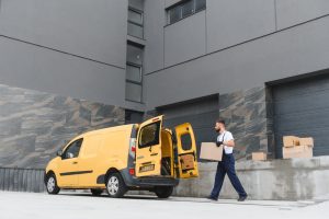Trabajador descargando mercancía de una van utilizada como vehículo comercial para un negocio.