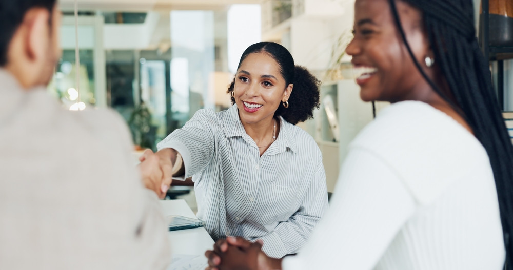 Asesora sonriente estrechando la mano de un cliente durante una consulta sobre cambiar de compañía de seguros con un SR-22.