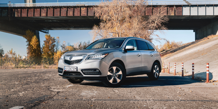 Acura MDX gris estacionado debajo de un puente.