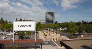 Letrero de "Concord", edificios y estacionamientos en la estación BART de Concord, California.