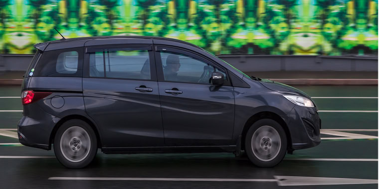 Mazda 5 gris oscuro en una autopista – seguro de auto barato para Mazda