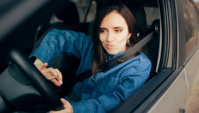 Mujer al volante de su auto con cinturón de seguridad, relacionado con cambiar de compañía de seguros mientras tienes un SR-22.