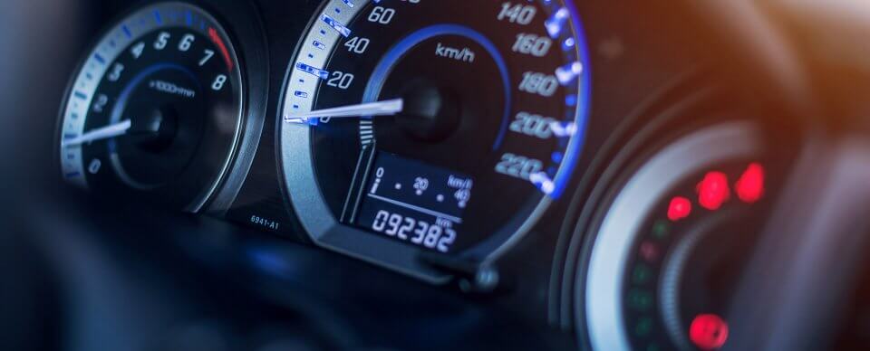 A close-up to the velocimeter of a car's dashboard to illustrate tips to keep mileage low with leased vehicles.