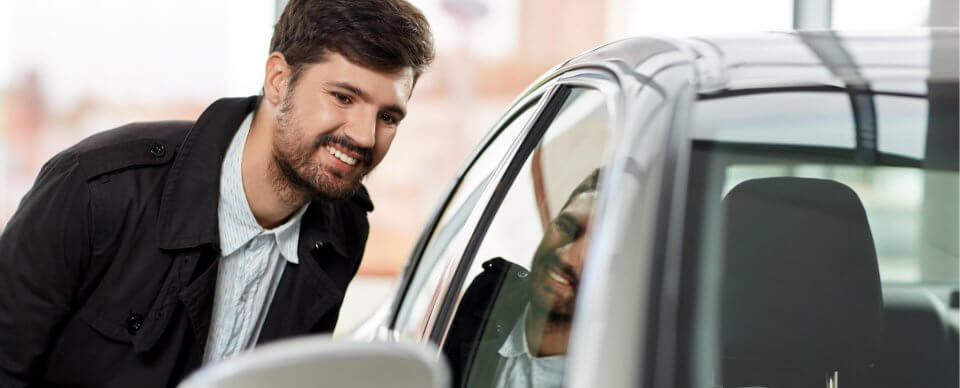 A young man inspecting a used car to illustrate 10 things to check before buying a used car.