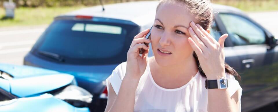 A worried woman making a phone call after hitting an uninsured motorist to illustrate what happens if you hit an uninsured motorist.