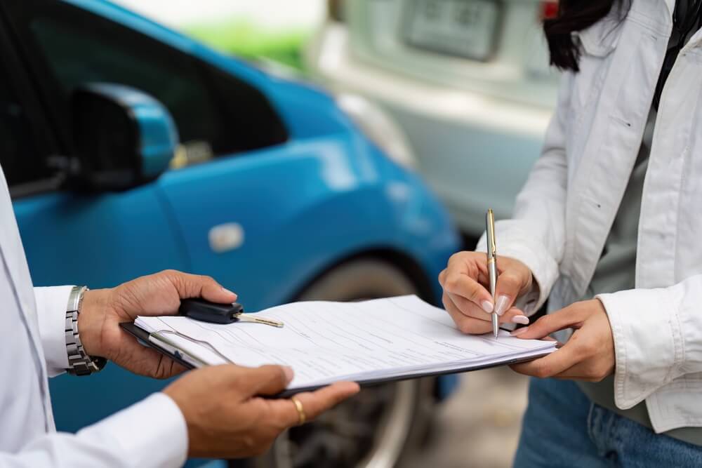 Driver signing insurance paperwork to reinstate coverage after an auto insurance lapse.