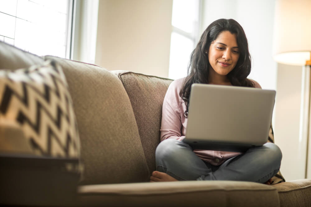 Hispanic woman looking to renew car insurance automatically on laptop