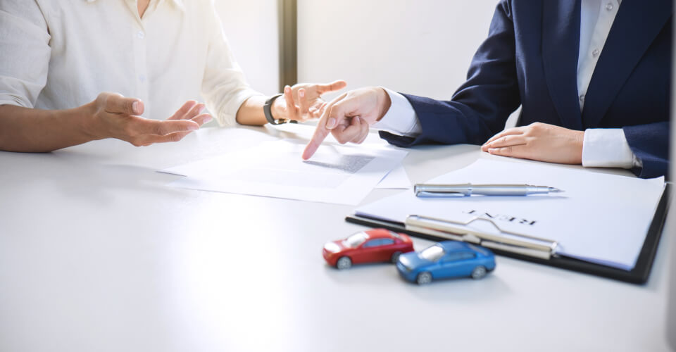 An insurance agent showing different options to a customer illustrating when is buying cheap car insurance online not a good idea.