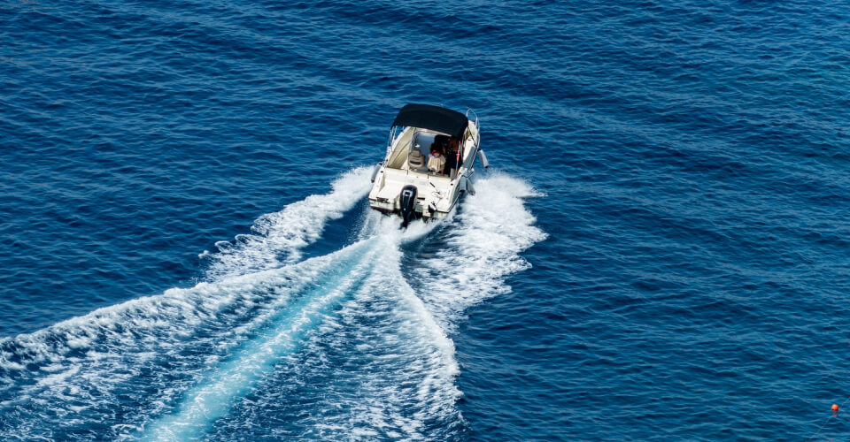 A small boat sailing in the big blue sea to illustrate if you need boat insurance when renting a boat.