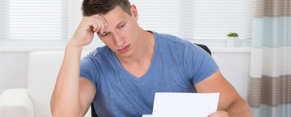 A man looks in exhaustion at an SR22 notice to showcase what does it mean to buy auto insurance.