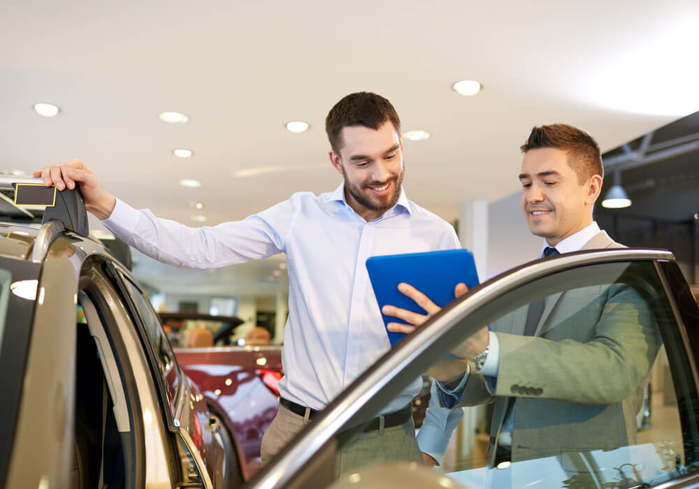 car salesman with customer selling a used car with insurance