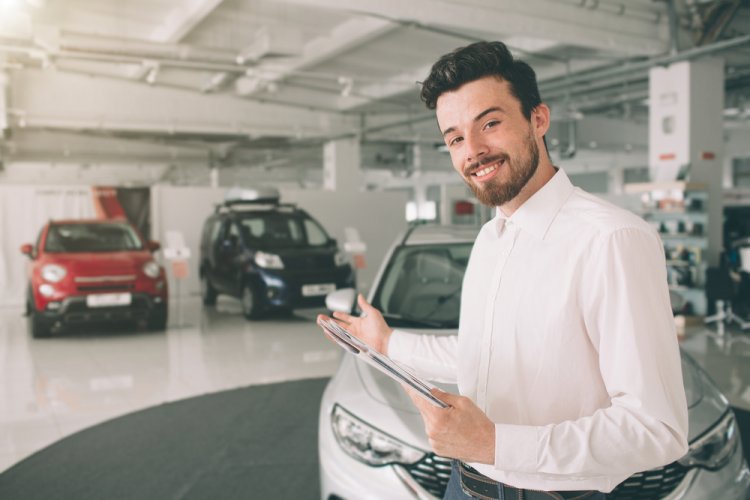 friendly car salesman looking at the camera to sell you a used car with insurance