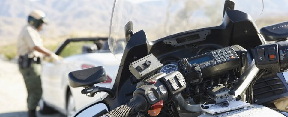 A traffic officer pulling over the driver of a convertible sportscar who will probably need an SR-22 after this.