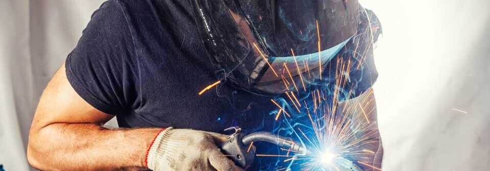 A man welding in full welding equipment with peace thanks to the protection of ADD insurance.