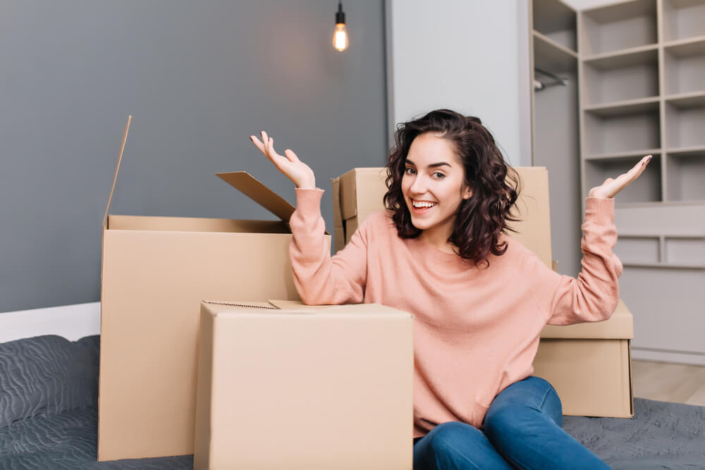 happy girl with boxes on apartment floor renters insurance