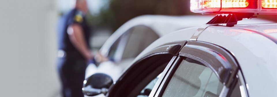 Close up of cop car and police officer approaching a vehicle after pulling it over for driving int he carpool lane.