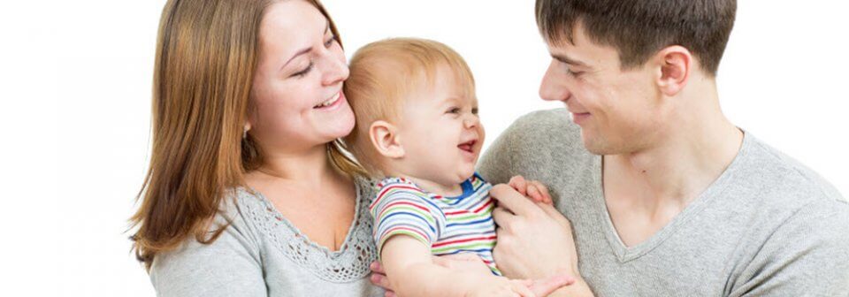 A young Caucasian family holding its young baby to illustrate how does having a baby lower can lower car insurance rates.