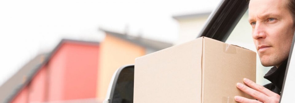 Man leaning out of car window holding small package to illustrate how does your auto insurance cover you for work related driving