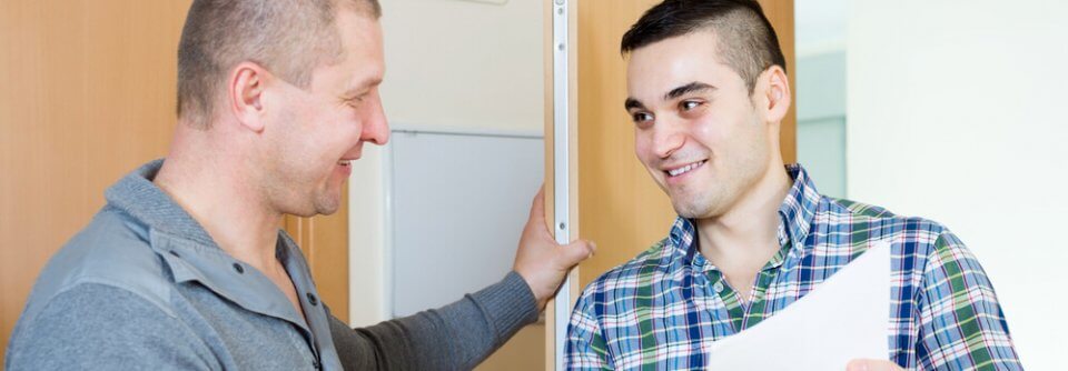 Smiling middle-age landlord and young tenant discussing document inside tenant's apartment