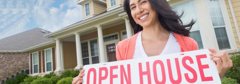 Smiling woman standing in front of house holding 