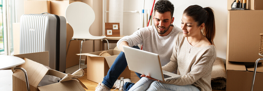 young couple looking for cheap renters insurance at kitchen table with laptop