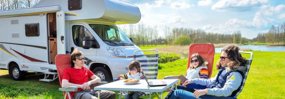 Family relaxing in front of their motorhome/RV thanks to the peace of mind that motorhome insurance offers