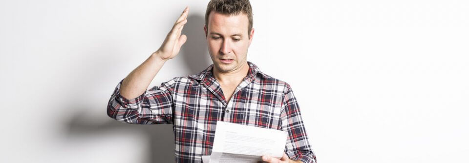 A Shocked man looking at auto insurance bill because the cost was much higher than what his insurance agent said it would