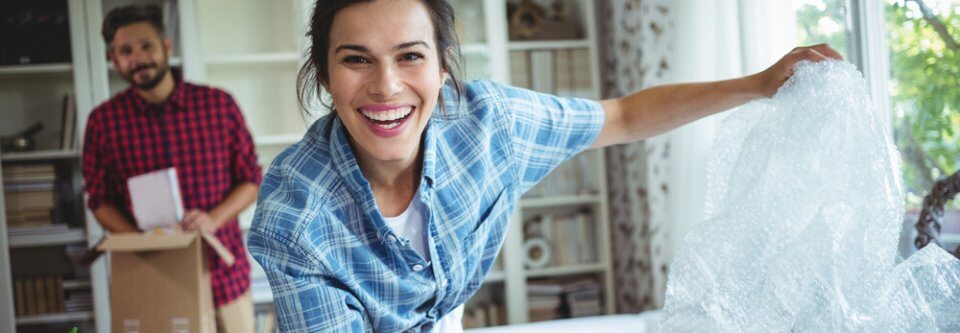 A happy latino couple who just moved into their new apartment portray how to save money on renter's insurance.