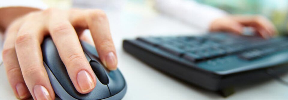 Close up of woman's hands on computer keyboard and mouse