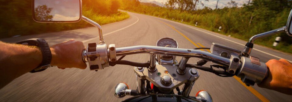 Photo of man riding motorcycle on open road taken from riders point of view to illustrate various motorcycle insurance thinks you should know.