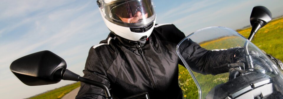 Close up of man riding motorcycle on open road to depict several tips for preventing a motorcycle accident.