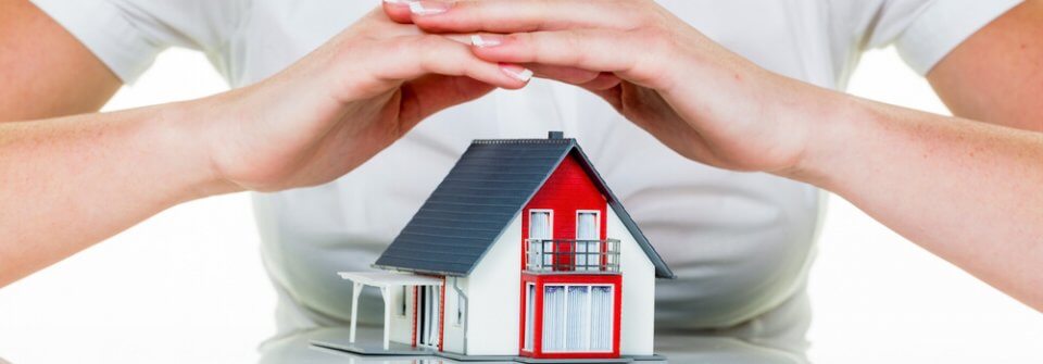 Woman holding her hands on a house render to illustrate what does homeowners' insurance cover.