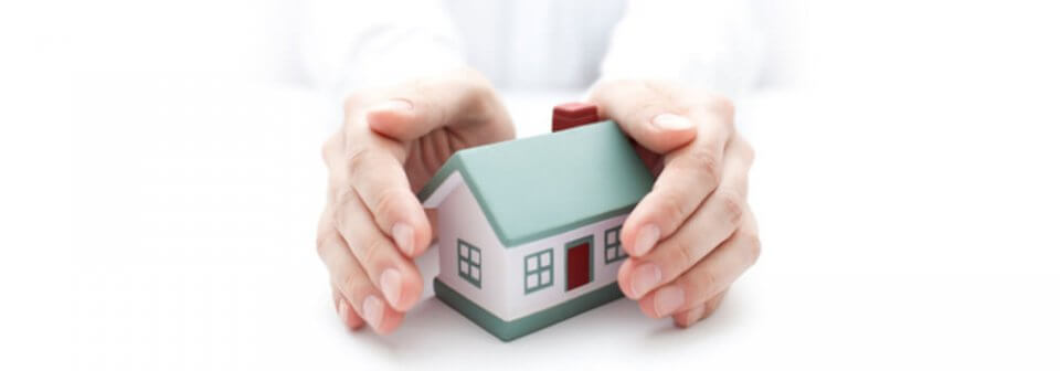 Close up of person protecting miniature house replica with hands to illustrate the importance of renter's insurance.