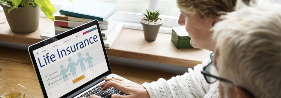 An elderly couple looking at a laptop screen that shows information about life insurance to illustrate what is permanent life insurance.