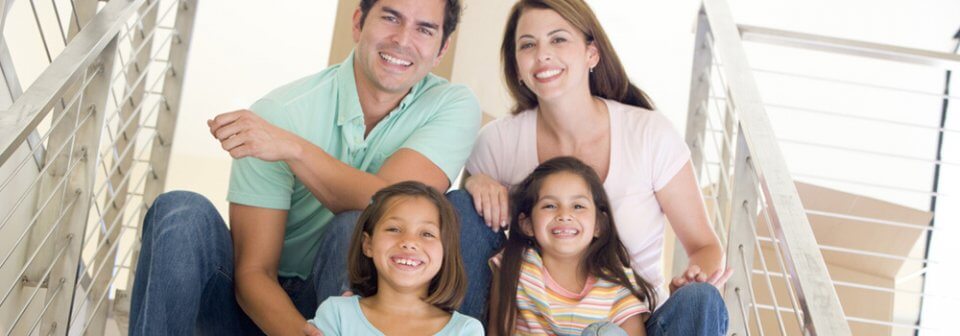 A young multi-ethnic family sit in the stairs of their apartment and illustrate what is renter's insurance.