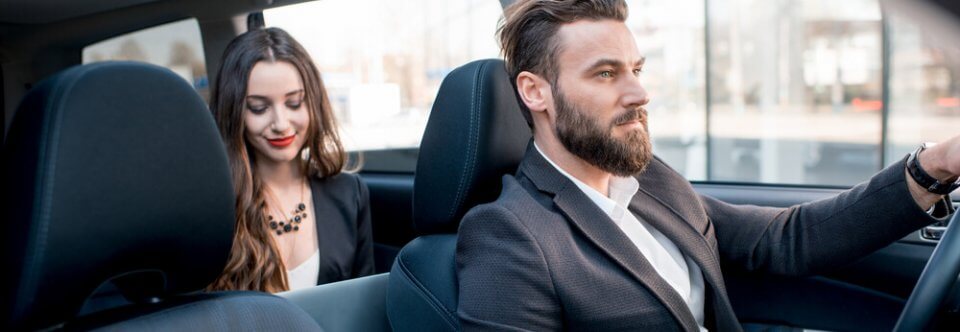A middle-age Cucasian businessman giving a lift to a young, Caucasian businesswoman and illustrating who needs commercial vehicle insurance