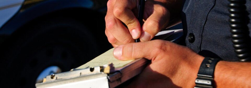 A traffic officer writing a ticket to a person and illustrating 10 things your insurance agent knows that you may not.