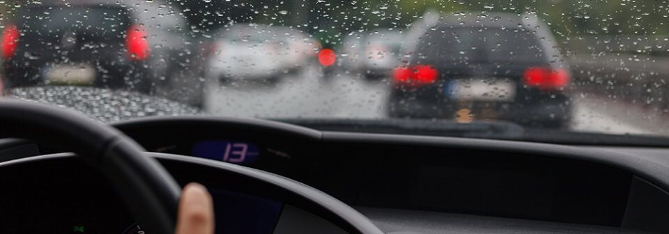 Point-of-view of a person driving in the rain that depicts 5 tips for driving safely in the rain.