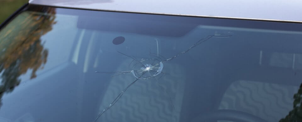 Close-up to a crack on a windshield that is covered by car insurance.