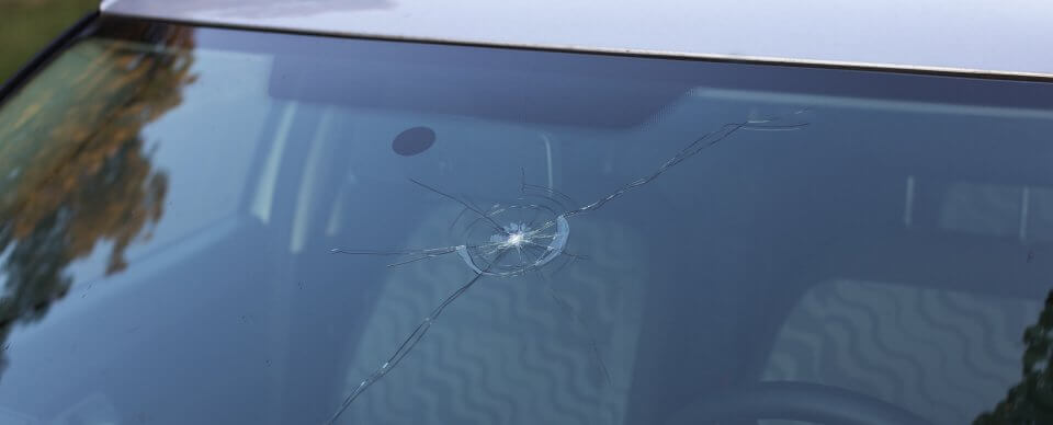 Close-up to a crack on a windshield that is covered by car insurance.