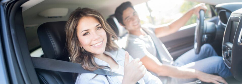 A young latino couple driving in their car and illustrating how SR-22 insurance works.