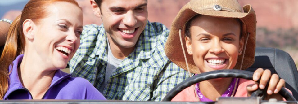 A group of young, Caucasian people driving on a sunny day to illustrate how to choose the right auto-insurance.