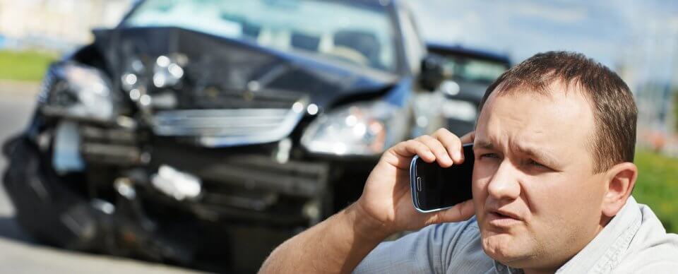 A Caucasian middle-aged man who was involved in a major car crash makes a phone call to illustrate when is a car a total loss.